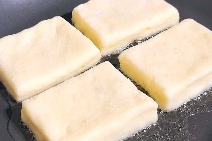 フライパンで焼かれている4つの四角い豆腐。