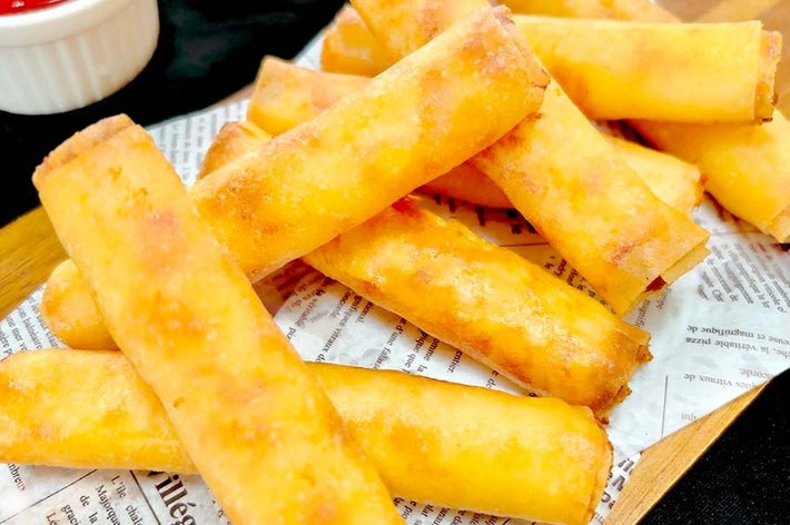 新聞の上に盛り付けられた揚げ春巻きと、小さなケチャップの器。