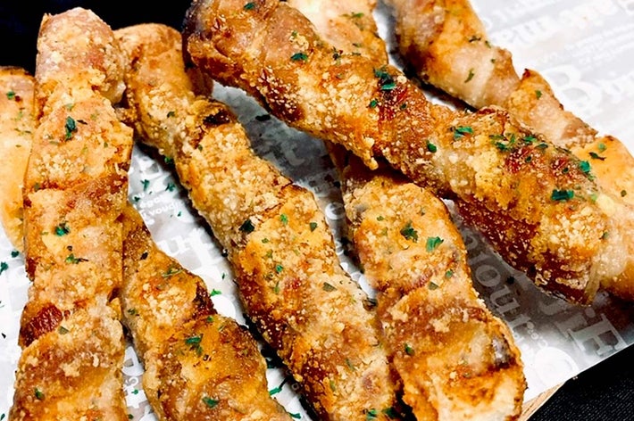 パセリが載ったチーズ味のガーリックブレッドスティックが並べられている。