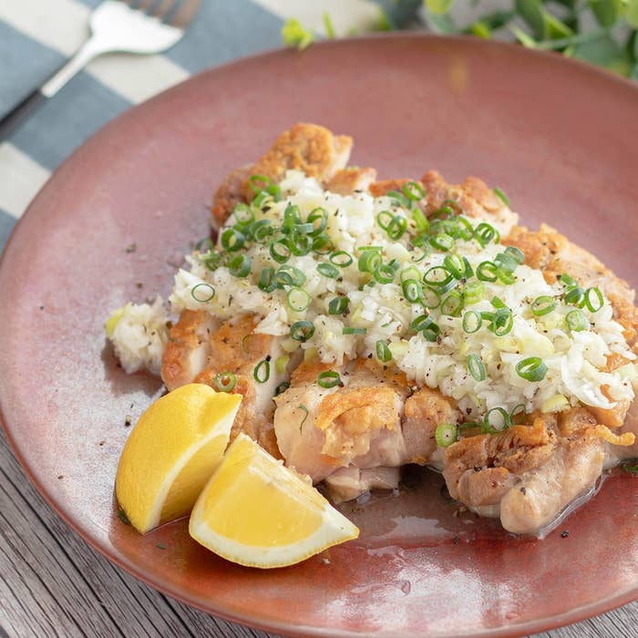 レモンとネギが添えられた、おろしポン酢チキン料理が盛られたプレート。