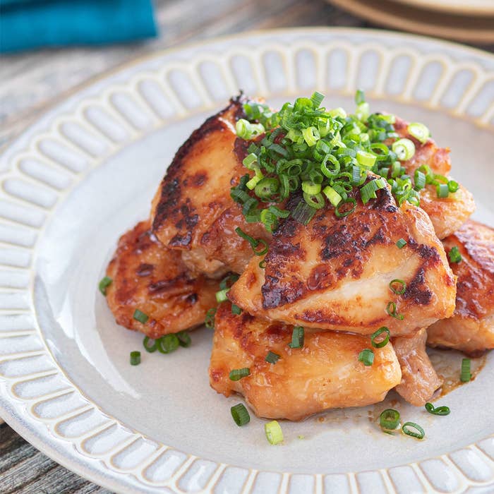 鶏肉のグリルにネギがトッピングされた料理が皿に盛られています。