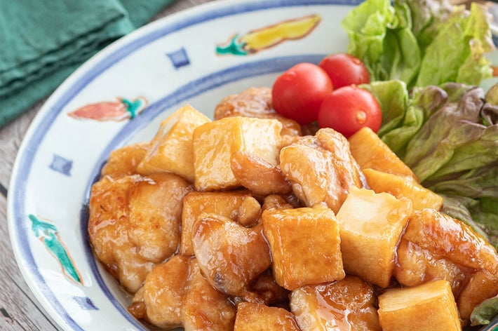 お皿に盛られた照り焼きチキンと豆腐の料理。トマトとレタスが添えられている。