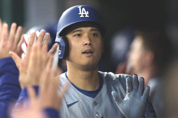 野球選手が試合中に多くのチームメイトからハイタッチを受けている。