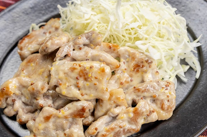お皿に盛られた粒マスタードソースをかけた豚こま肉と千切りキャベツ。