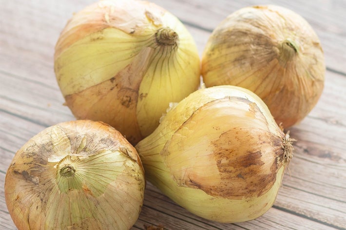 木製の表面に置かれた4つの玉ねぎ。