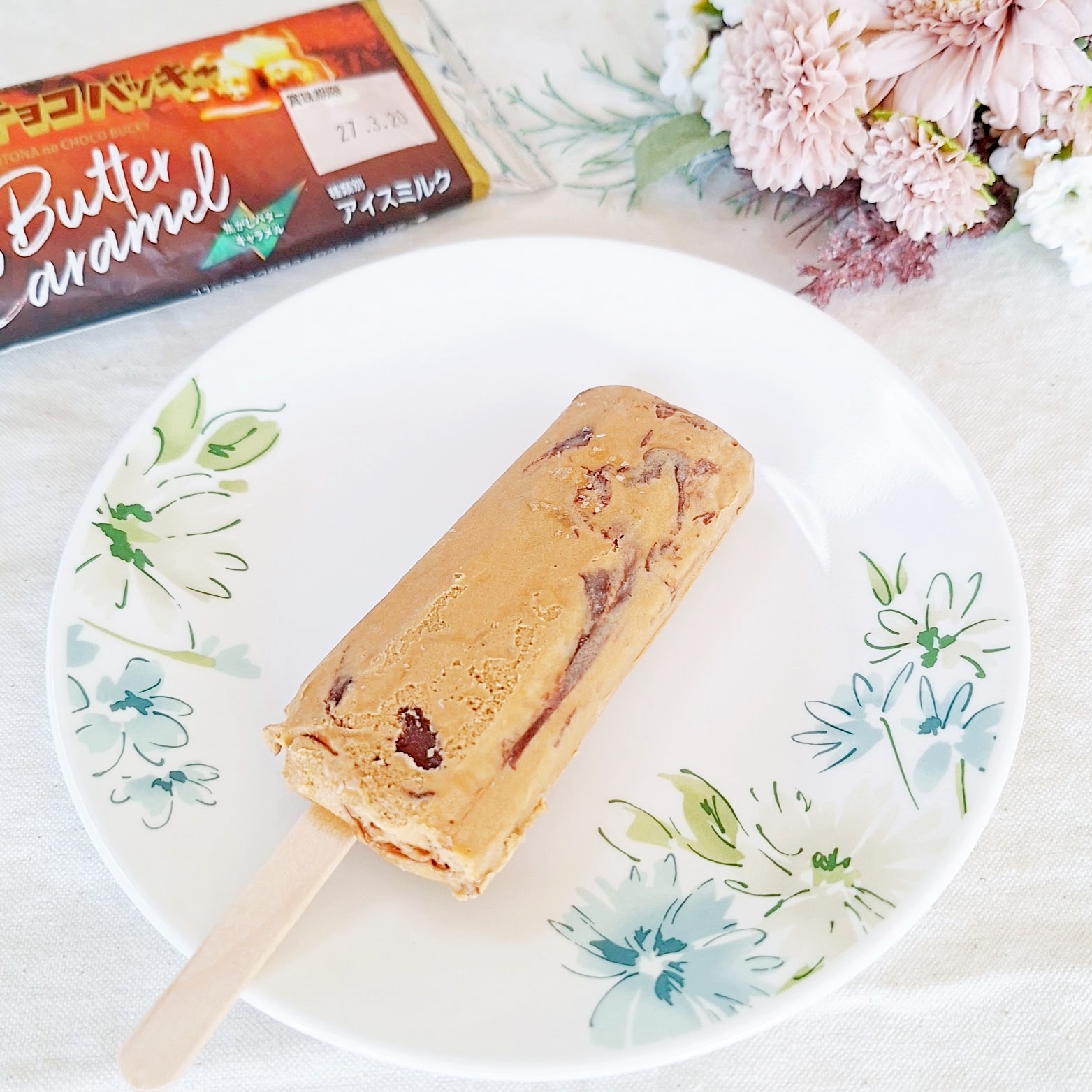 皿に盛られたバターキャラメルアイスキャンディー。背景に花とキャラメルのパッケージ。