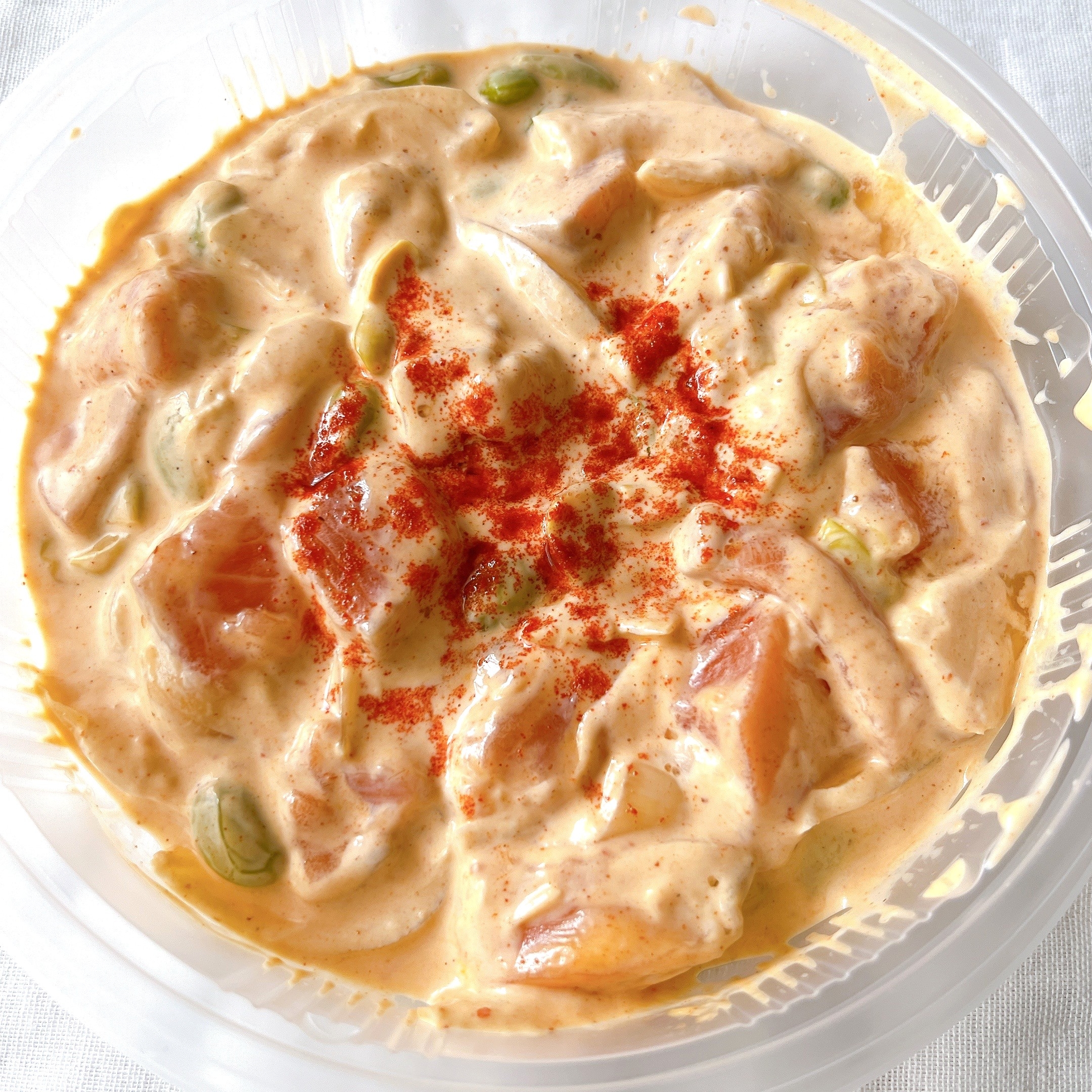 プラスチック容器に入ったスパイシーサーモンポキ。