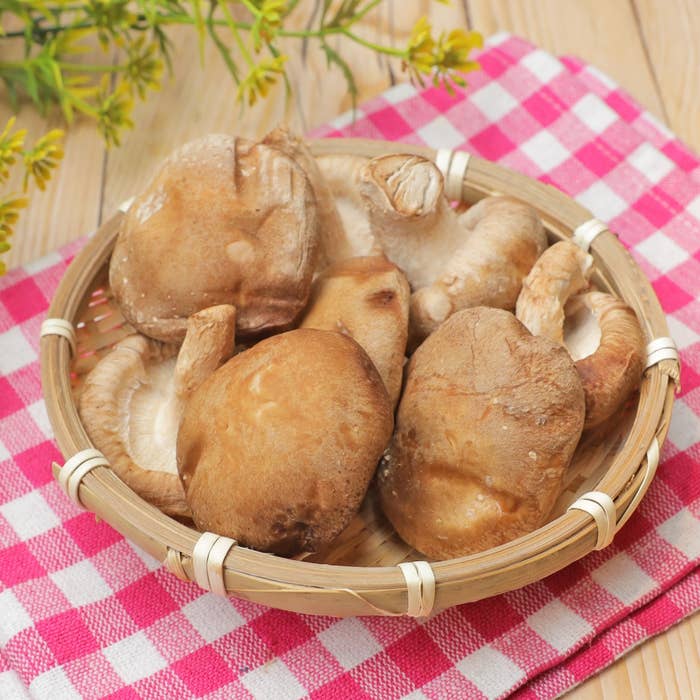 竹ざるに盛られたしいたけ。テーブルにはチェック柄のクロスが敷かれている。