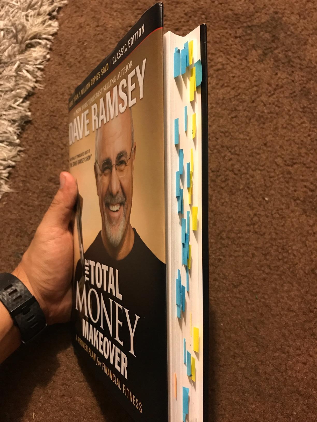 Person holding "The Total Money Makeover" book by Dave Ramsey