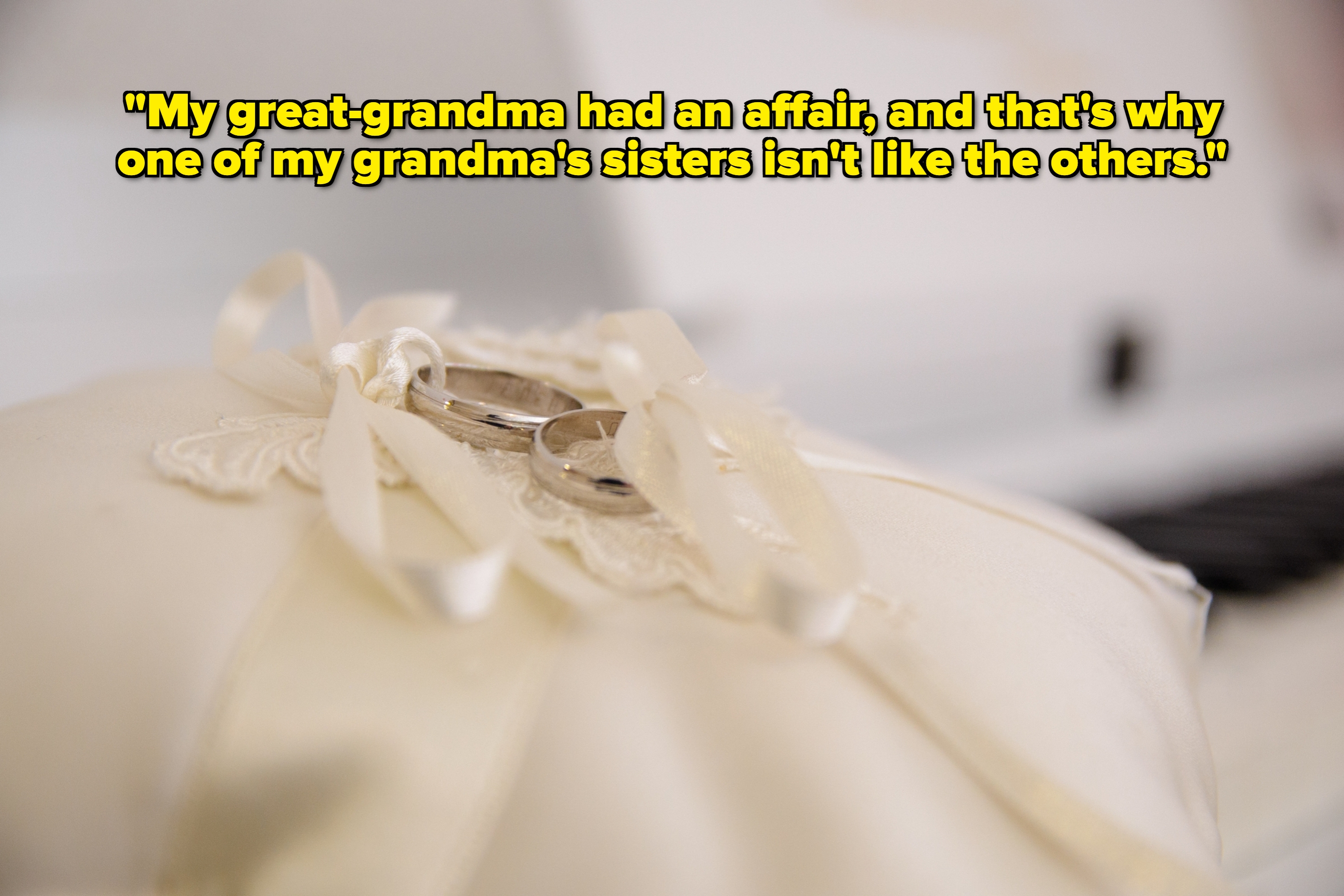 Close-up of two wedding rings tied with ribbons on a pillow, set on a piano