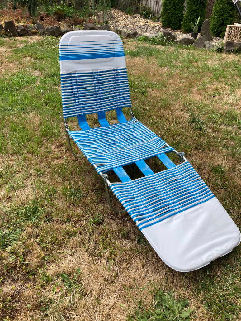 Striped lawn chair set on grass in a backyard