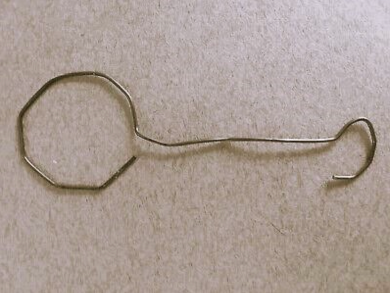 A wire bent into the shape of a key lies on a flat surface