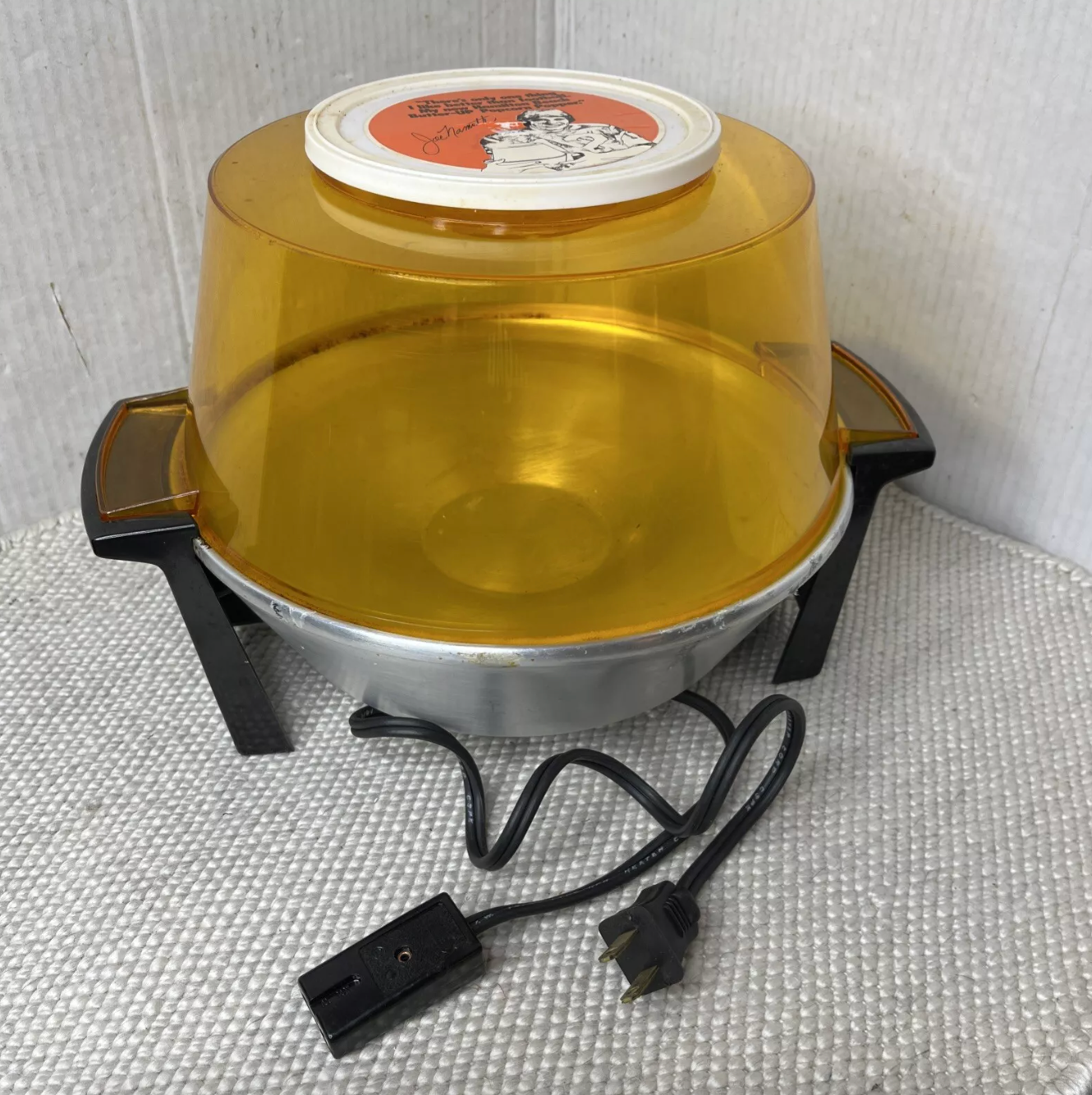 Air-popper popcorn maker with a domed top and attached electric cord, set on a textured surface