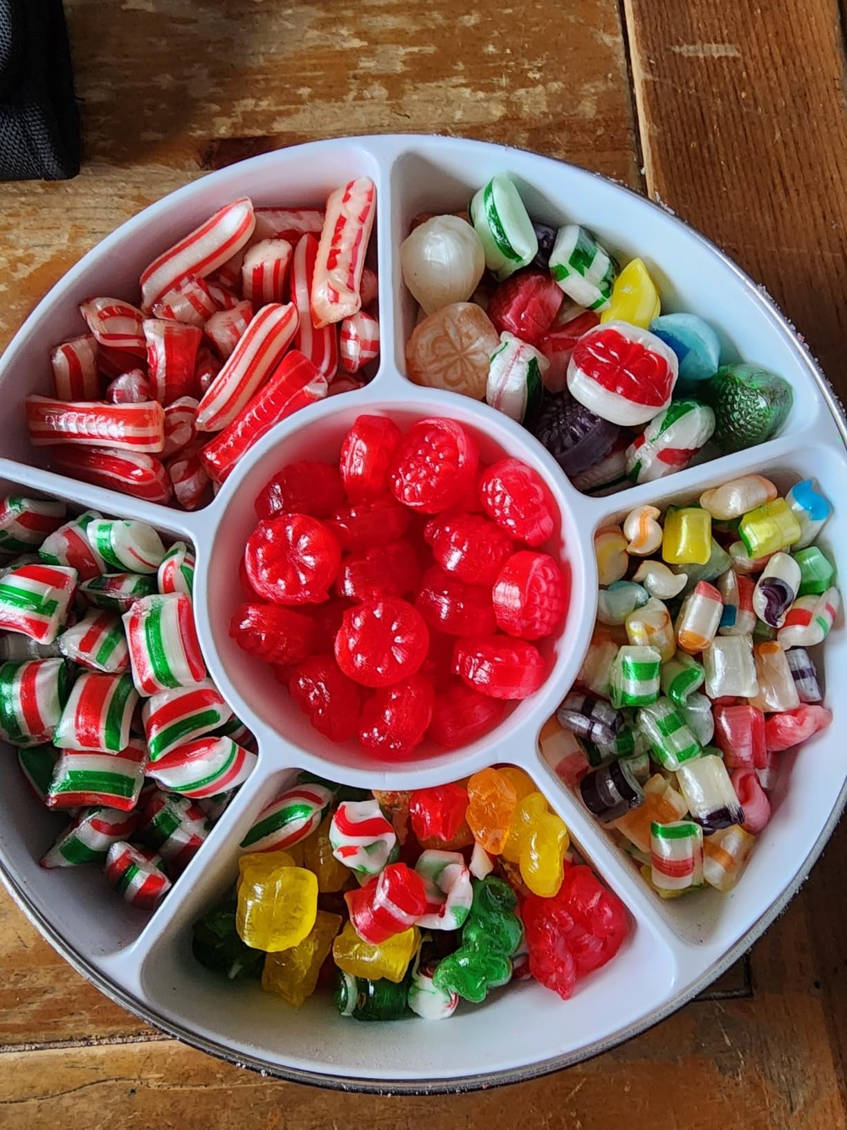Tray with assorted candies, including gummy bears, peppermints, and fruit-shaped sweets, arranged in separate compartments
