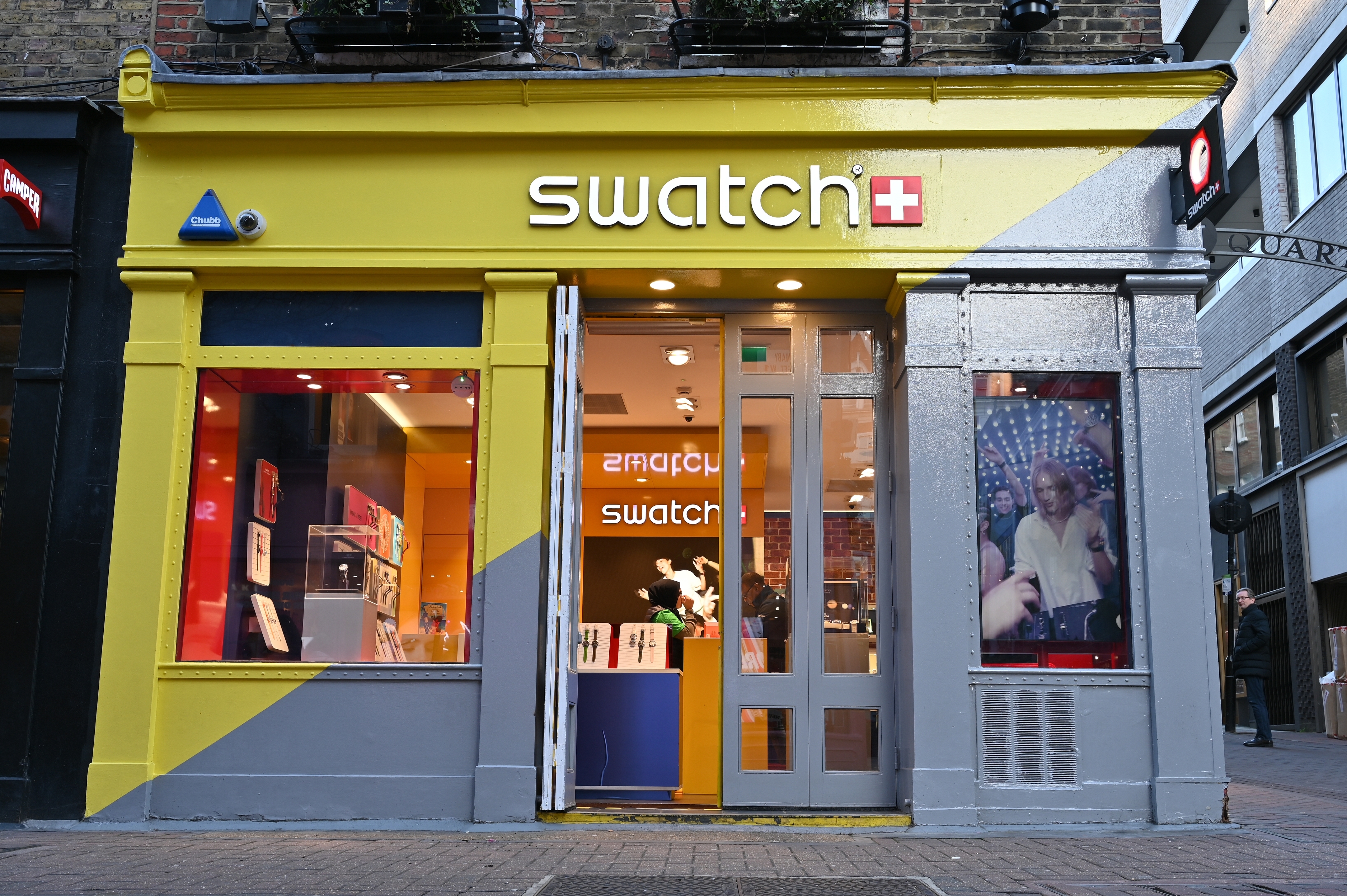 Front view of a Swatch store with colorful signage and window displays, located on a city street