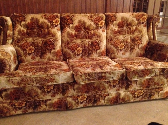 Vintage floral-patterned couch with intricate design and plush texture, set against a wood-paneled wall
