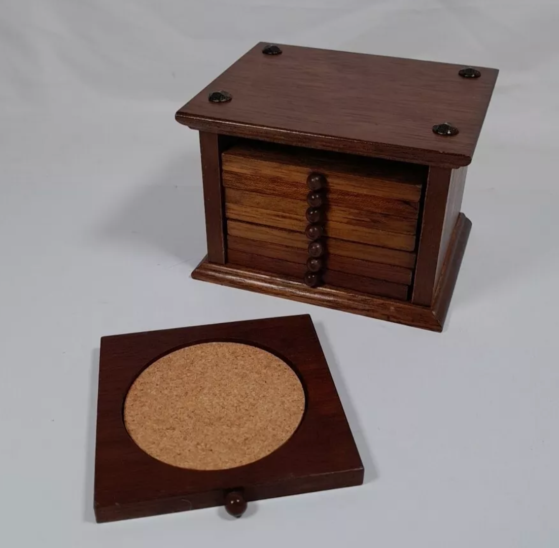 Wooden coaster set with a box and a coaster holder. The coasters have a circular cork center and the box features decorative round knobs