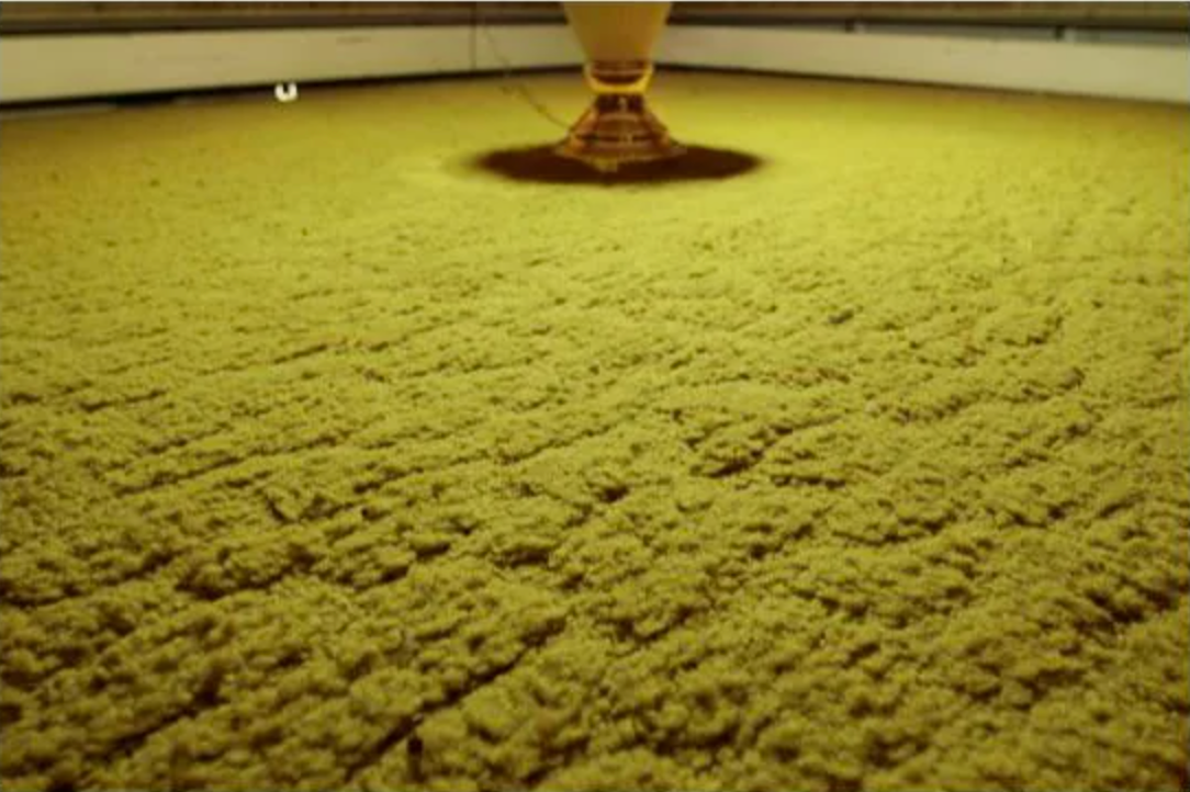 A large, textured surface with a central cone-shaped object, resembling a unique manufacturing or food production process