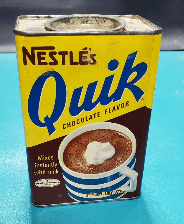 Vintage Nestlé Quik tin with a cup of chocolate and whipped cream, labeled "Mixes instantly with milk."