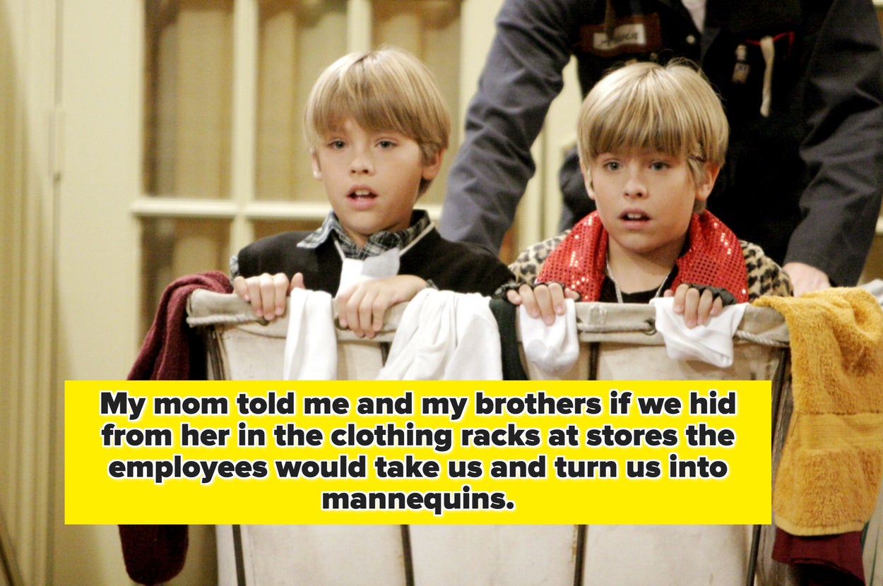 Two children with blonde hair peer over a large laundry bin, looking intrigued. They wear casual clothes and stand indoors