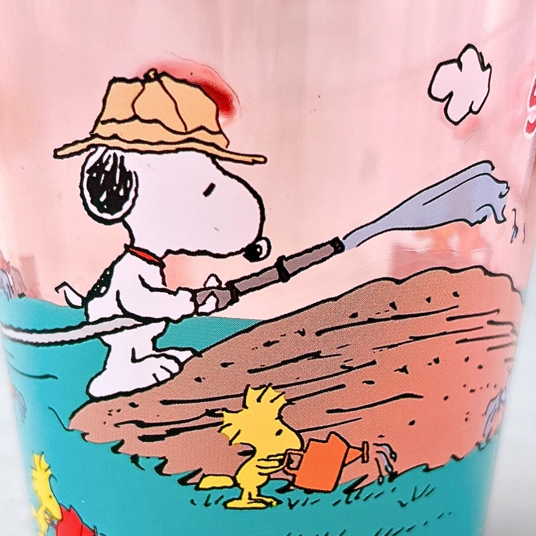 スヌーピーが探検帽をかぶり、ウッドストックと一緒にホースで放水している可愛らしいイラスト。