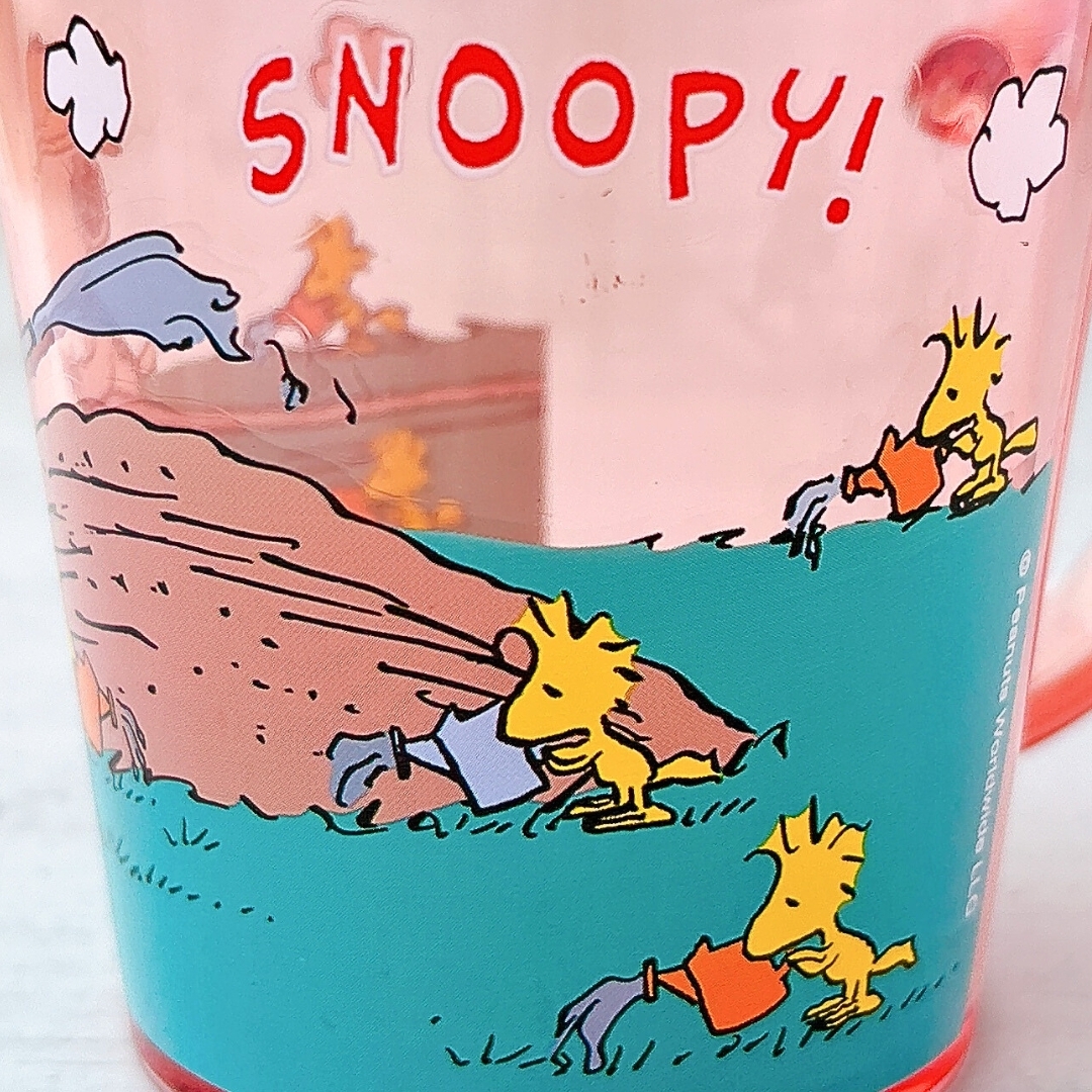スヌーピーマグカップのデザイン。ウッドストックと仲間たちが芝生で活動しています。上部に「SNOOPY!」のテキスト。