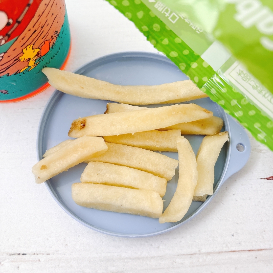 皿の上にスティック状のポテトスナックが並べられている。隣に野菜ジュースのパックが見える。
