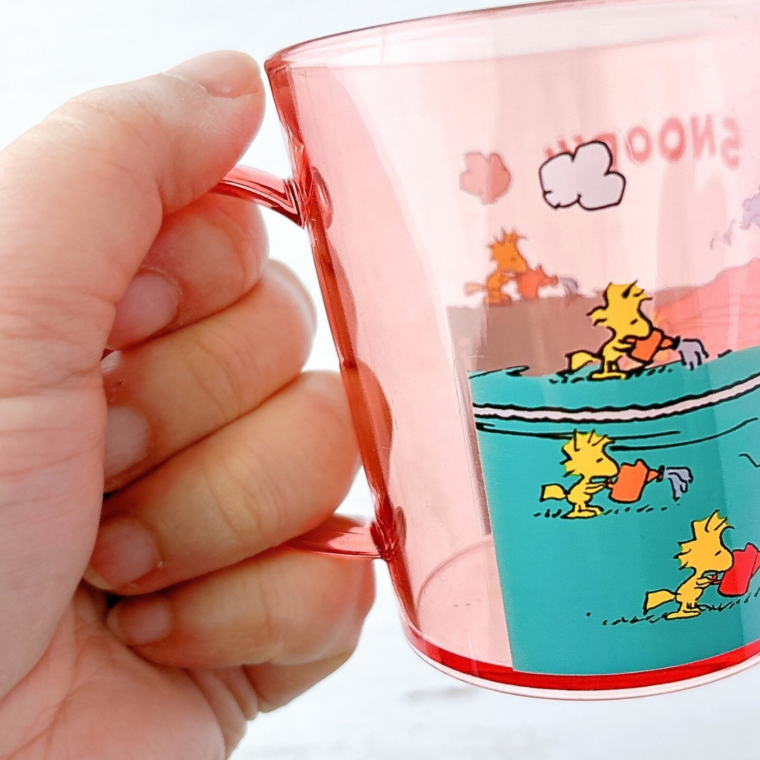 手に持たれたカップには、スヌーピーが描かれたデザインが特徴です。