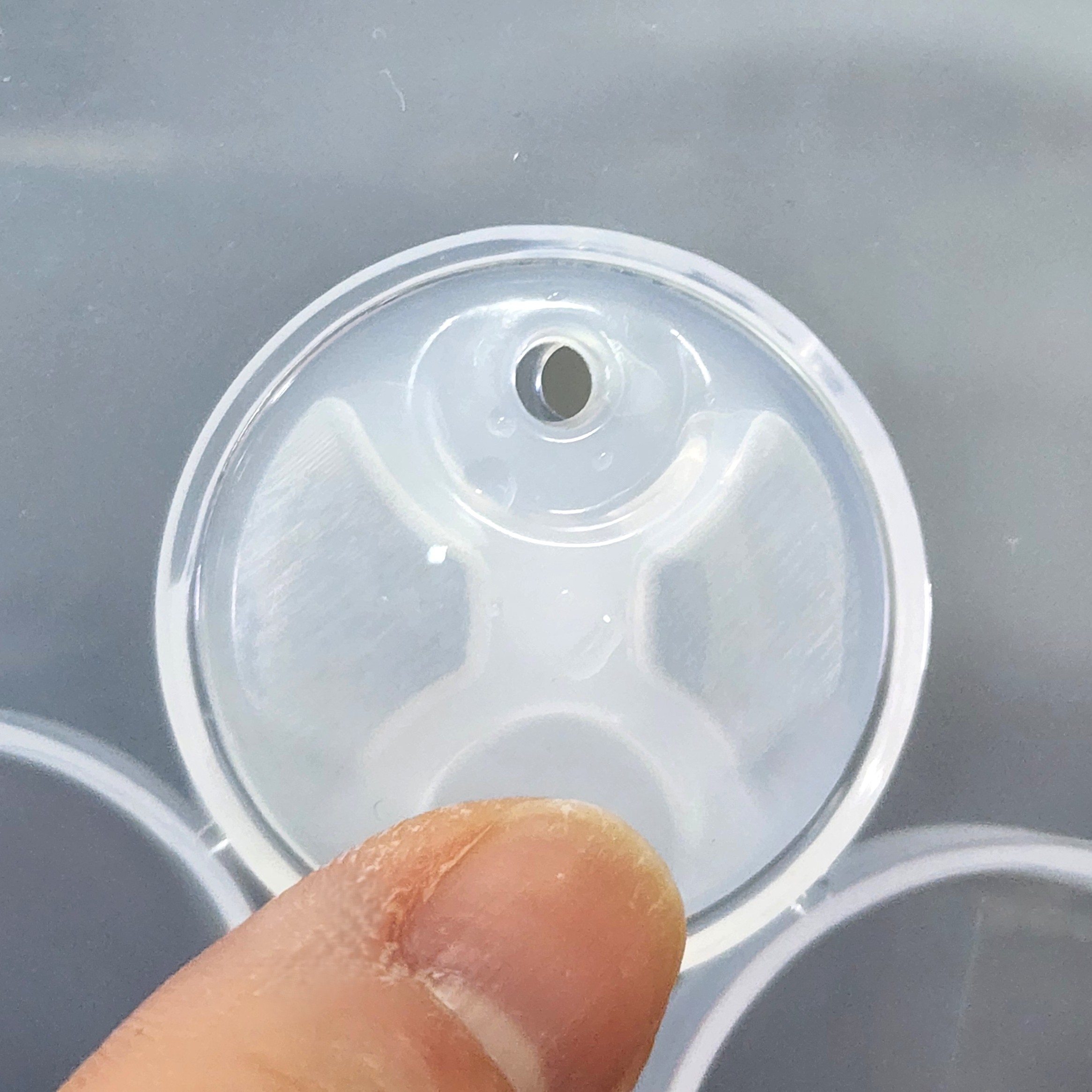 透明なプラスチック製の印象トレイを指で持っている様子。