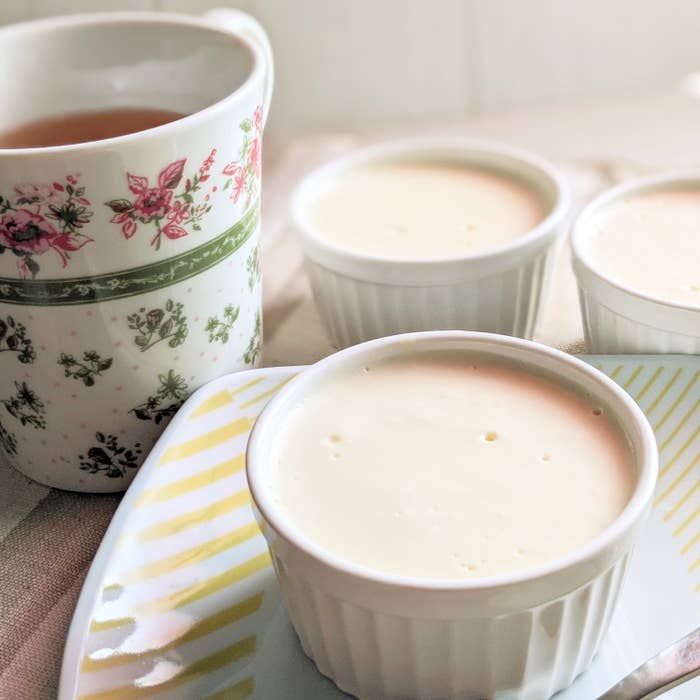 ティーカップと3つの小さな白いカップに入ったデザートがテーブルに置かれている。