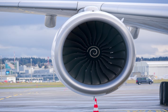 飛行機のターボファンエンジンのクローズアップ。滑走路と空港の背景が見える。