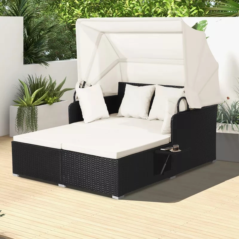 Outdoor double lounge chair with canopy and cushions on a patio, surrounded by potted plants. Perfect for relaxing or sunbathing