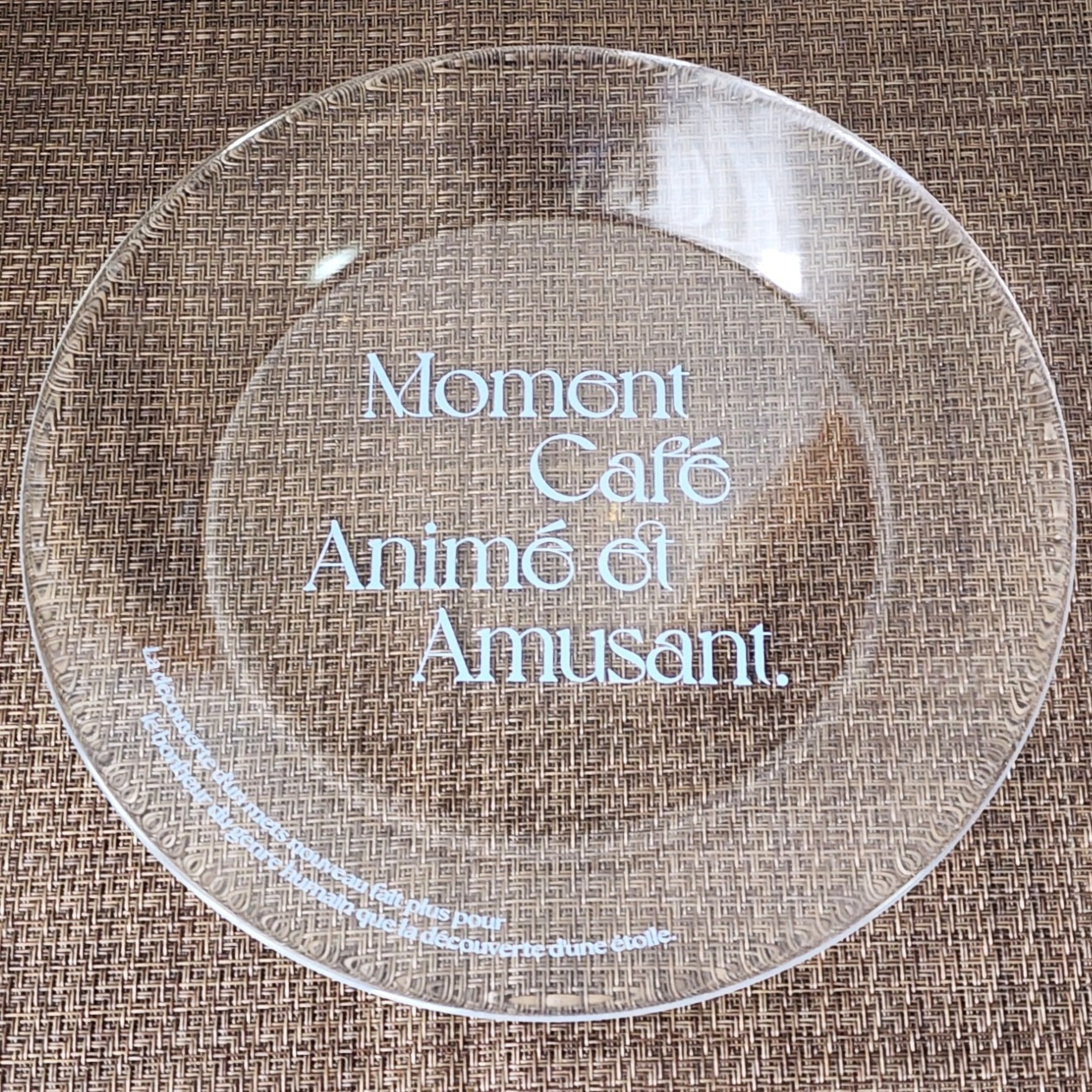 透明な皿に「Moment Café Animé et Amusant」と書かれたテキスト。フランス語で楽しげなカフェの瞬間を表現しています。