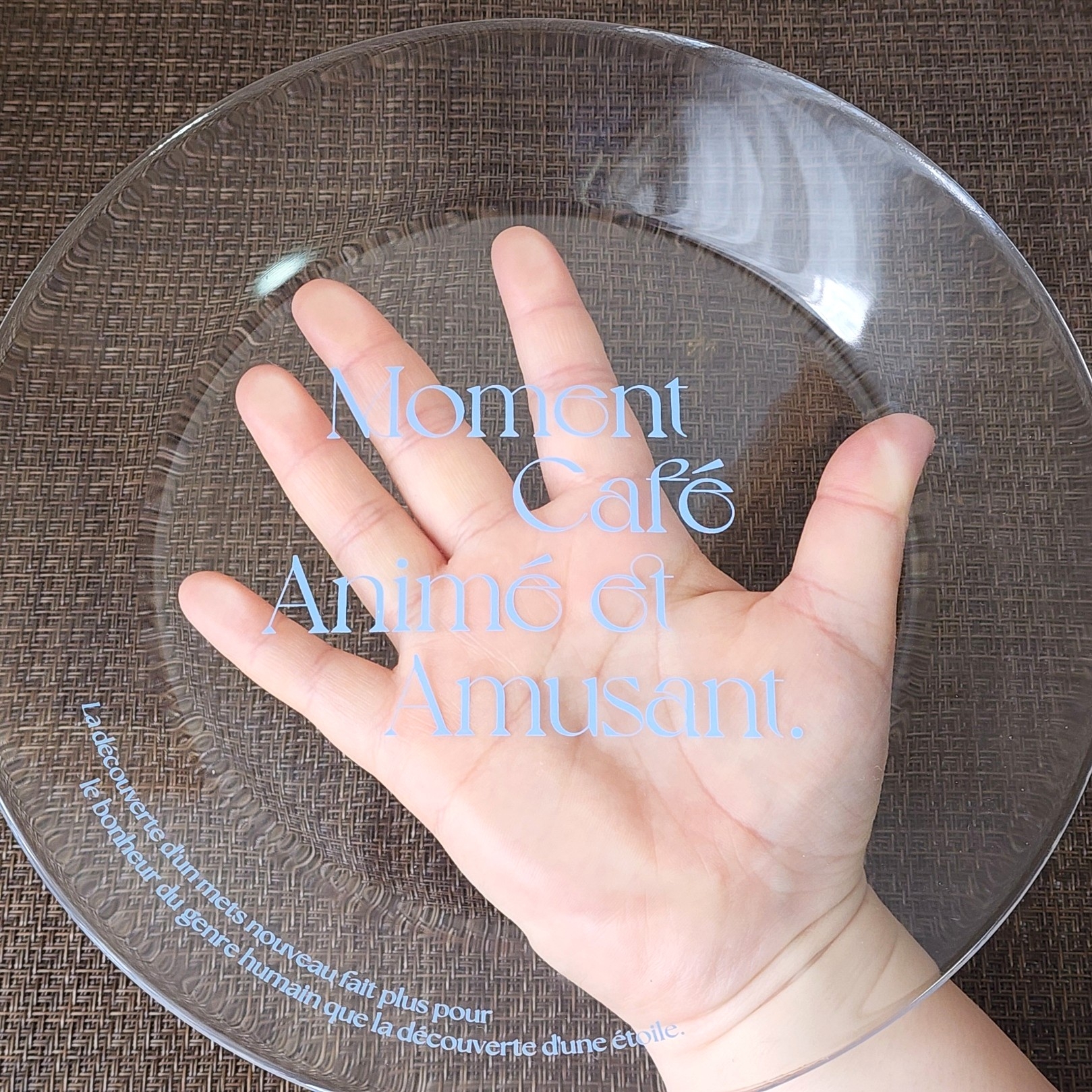 手に透明なプレートが乗っており、「Moment Café Animé et Amusant」の文字が見える。