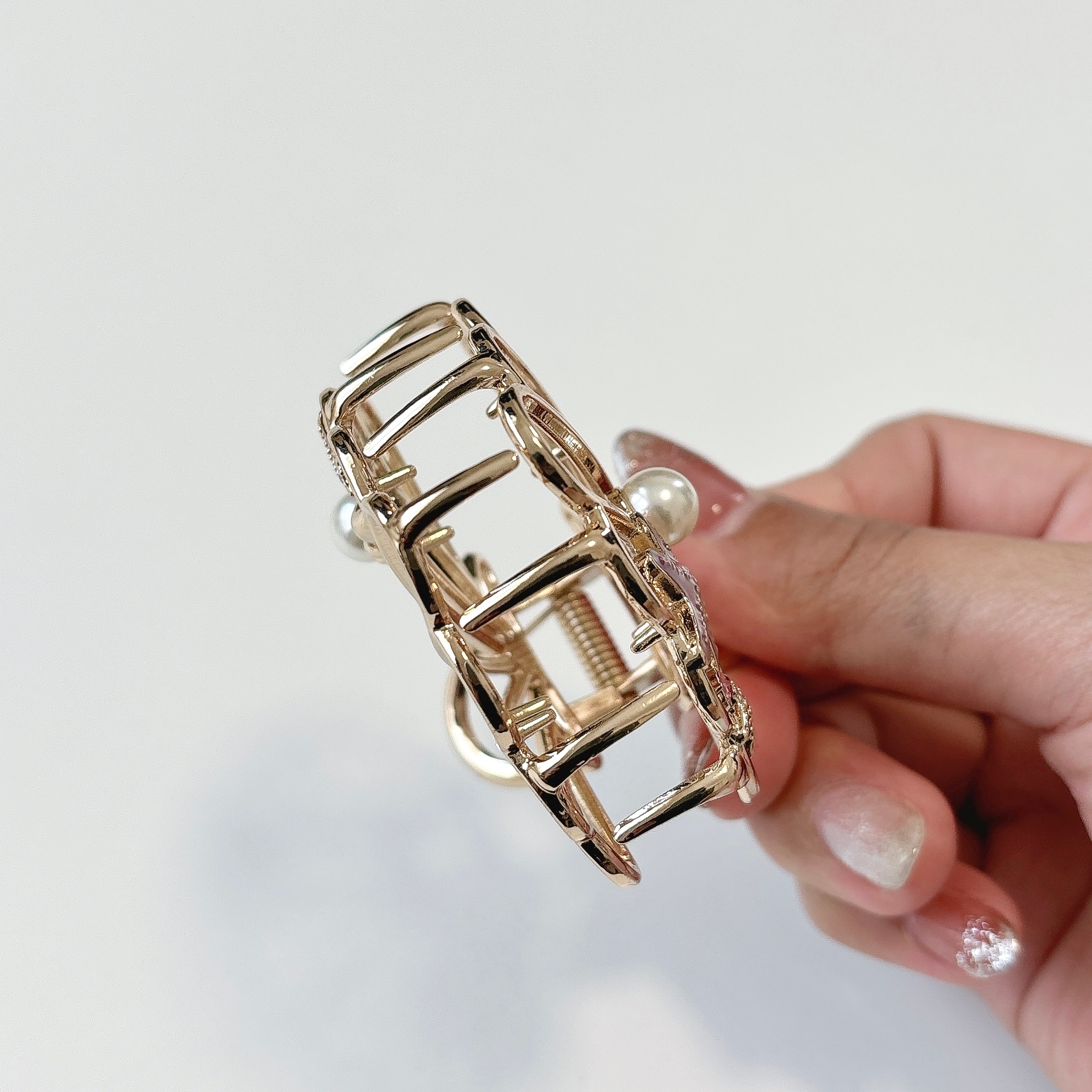 手に持たれた金属製のヘアクリップ。几帳面なデザイン。