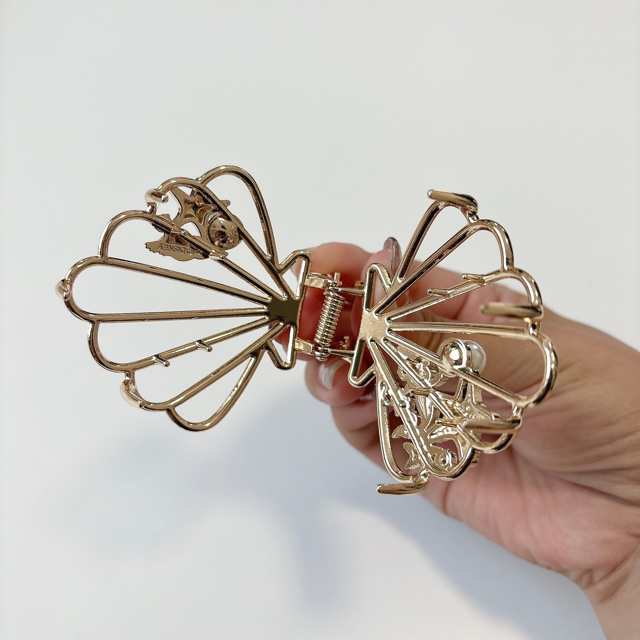 手に持たれた蝶の形をした金属製のヘアクリップ。