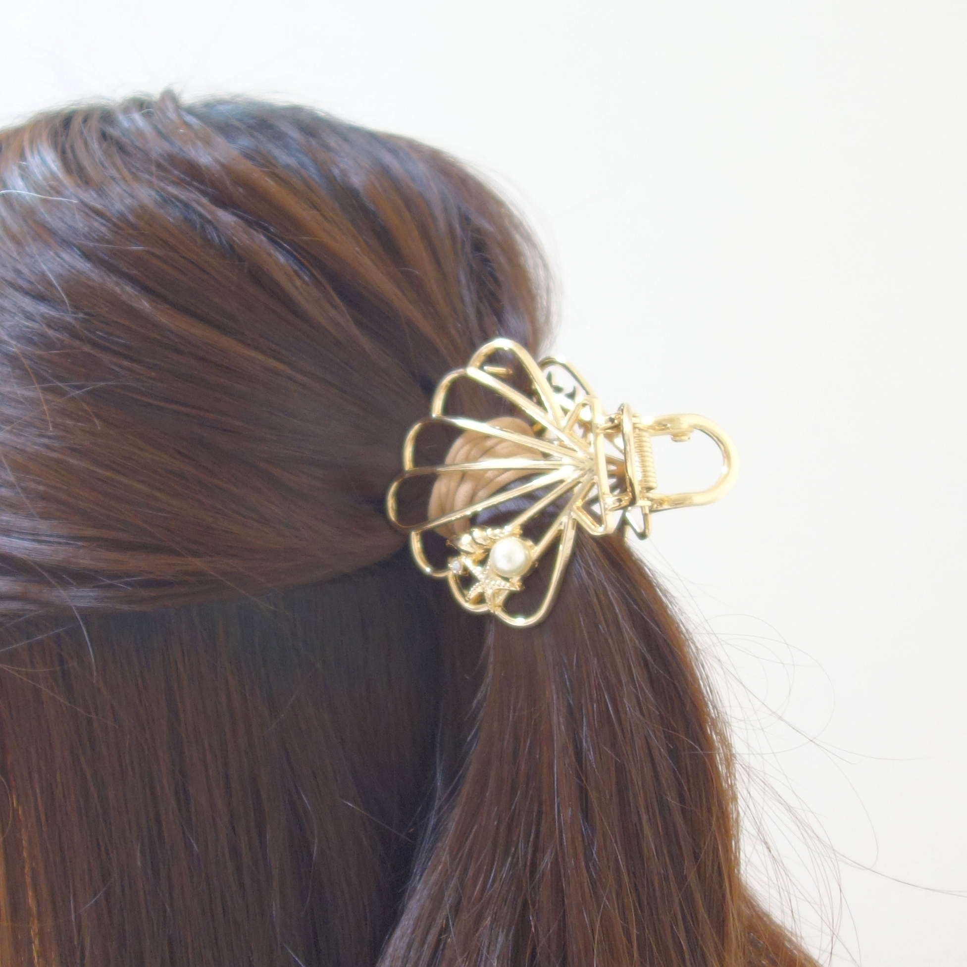 髪にゴールドの髪留めをつけた人の横顔。髪留めはデザイン性があり、装飾として強調されている。