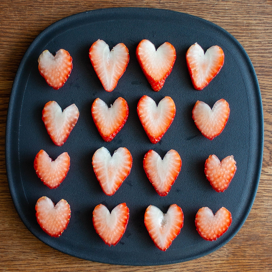 ハート型に切られたイチゴが黒いプレートに並んでいる。