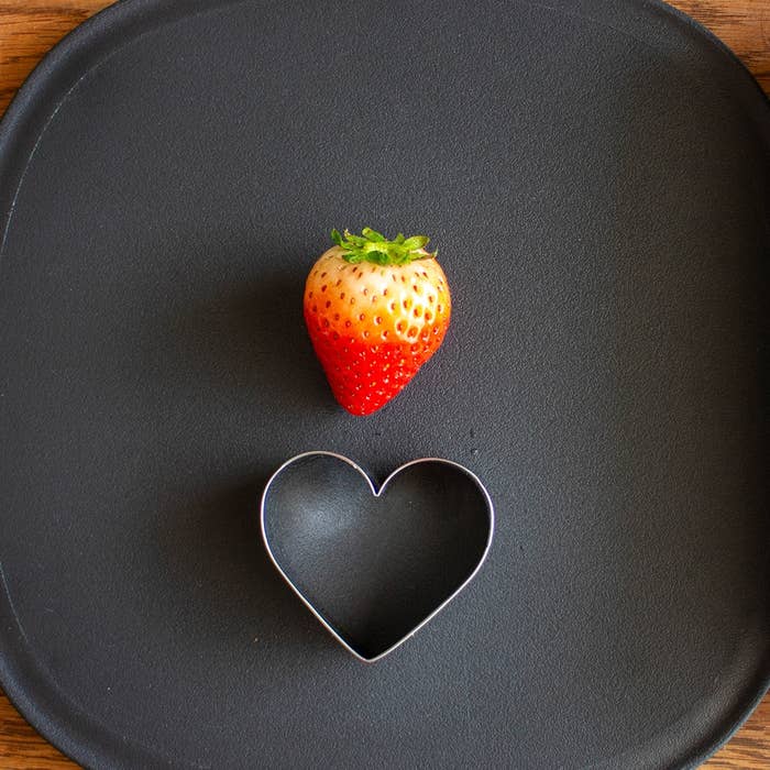 黒い皿の上に置かれたイチゴとハート型のクッキー型。