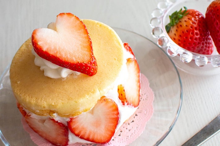 クリームとスライスしたイチゴを乗せたスポンジケーキがガラス皿に盛り付けられ、横にイチゴの小鉢があります。