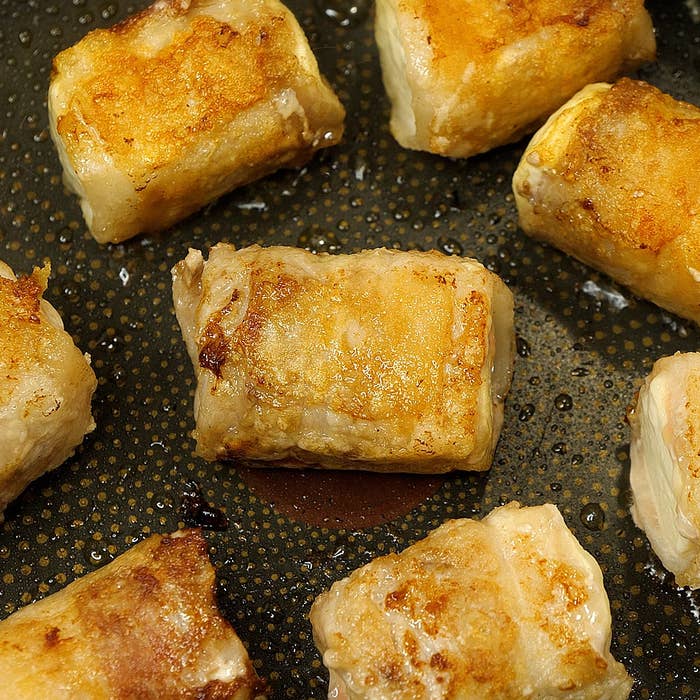 焼き色のついた春巻きが油で揚げられている様子。