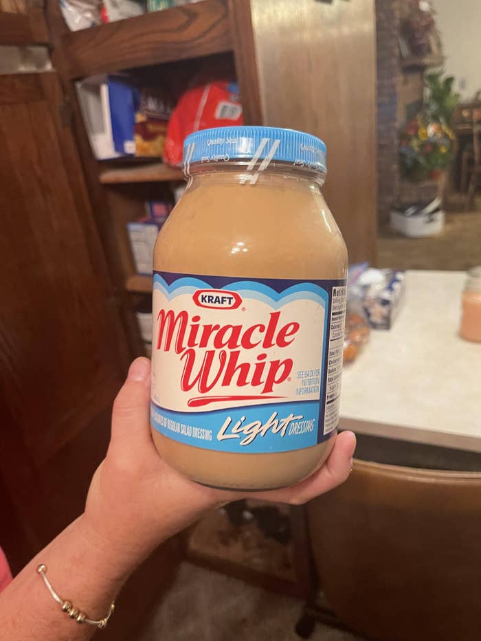 A person holds a jar of Kraft Miracle Whip Light in a kitchen setting