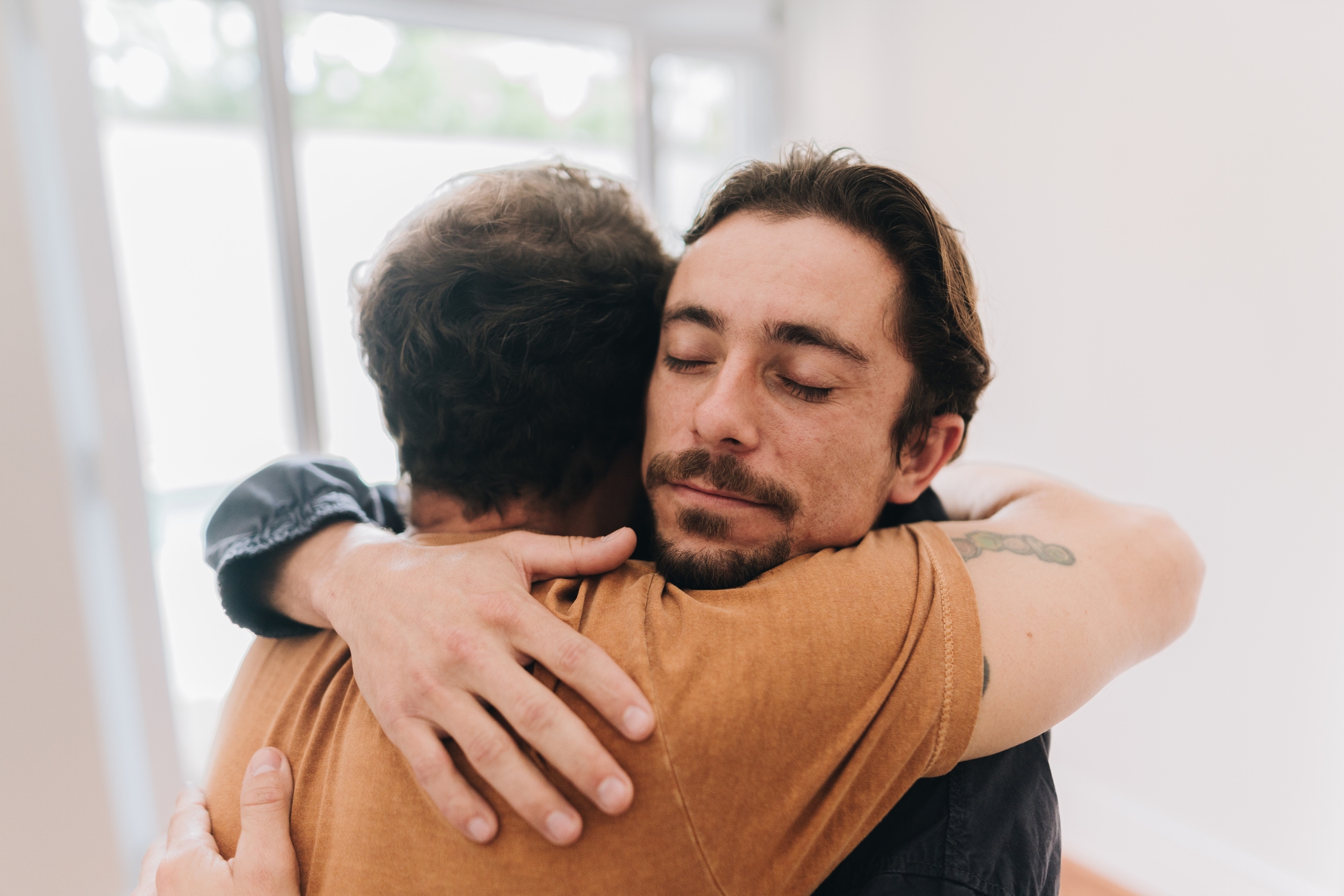 Two people warmly hugging each other indoors, conveying a sense of support and affection