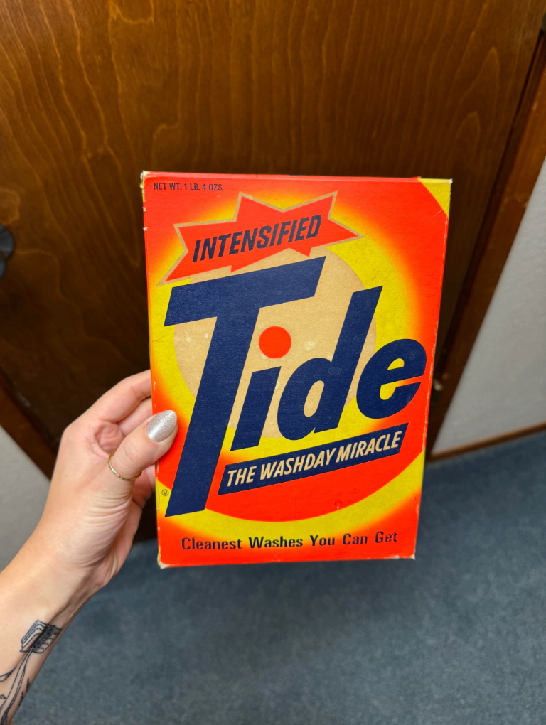 Person holding a vintage Tide detergent box labeled "Intensified Tide: The Washday Miracle—Cleanest Washes You Can Get."