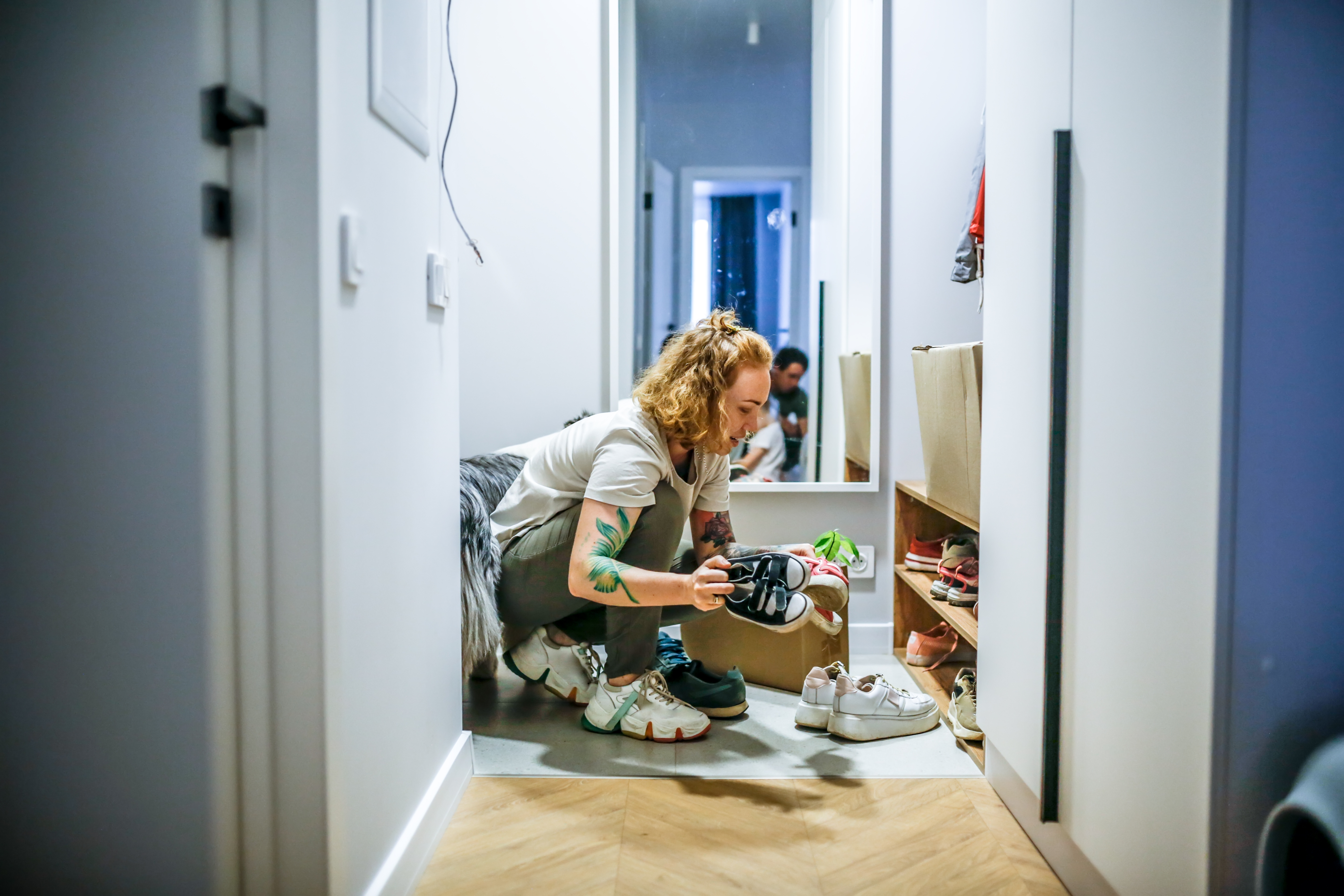 Person organiserer sko i en gang, plasserer et par i et rack
