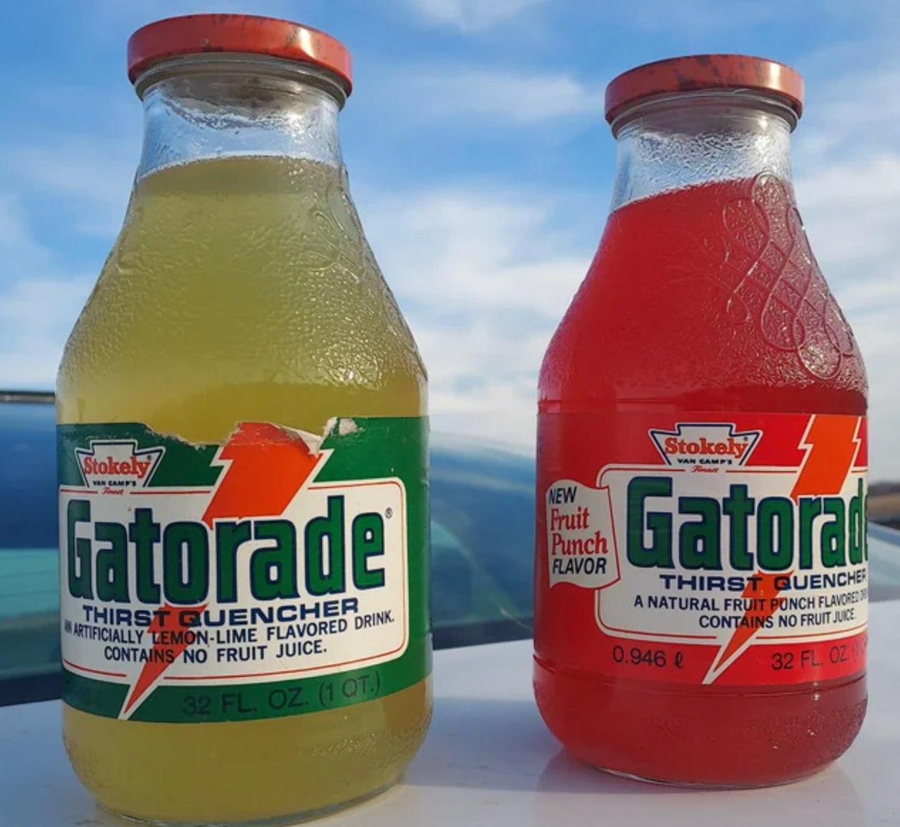 Two bottles of Gatorade: one lemon-lime, and one fruit punch flavor, displayed outdoors under a partly cloudy sky