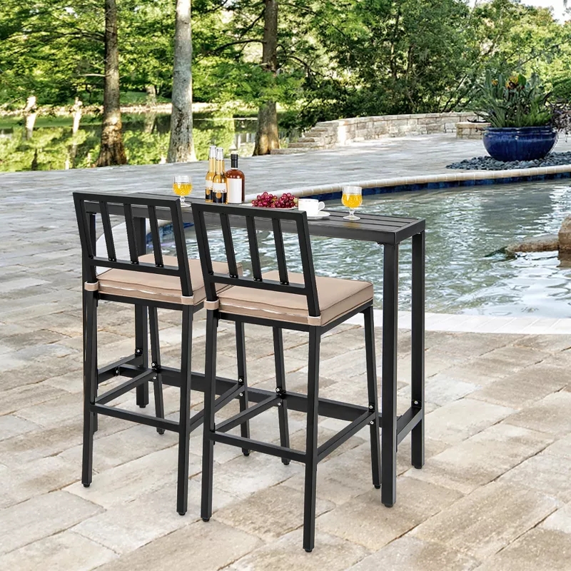 Outdoor patio set with two bar stools and a tall table near a pond, featuring wine, glasses, and snacks on the table