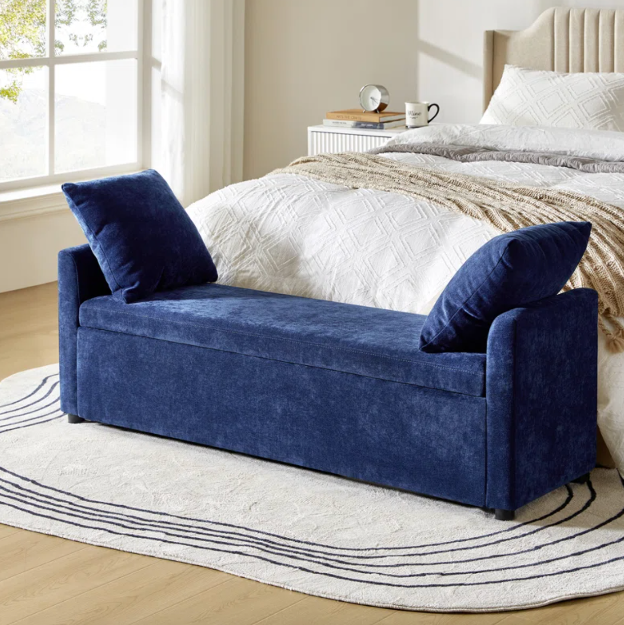 Bedroom with a blue upholstered storage bench at the foot of a bed, featuring two pillows and a cozy atmosphere