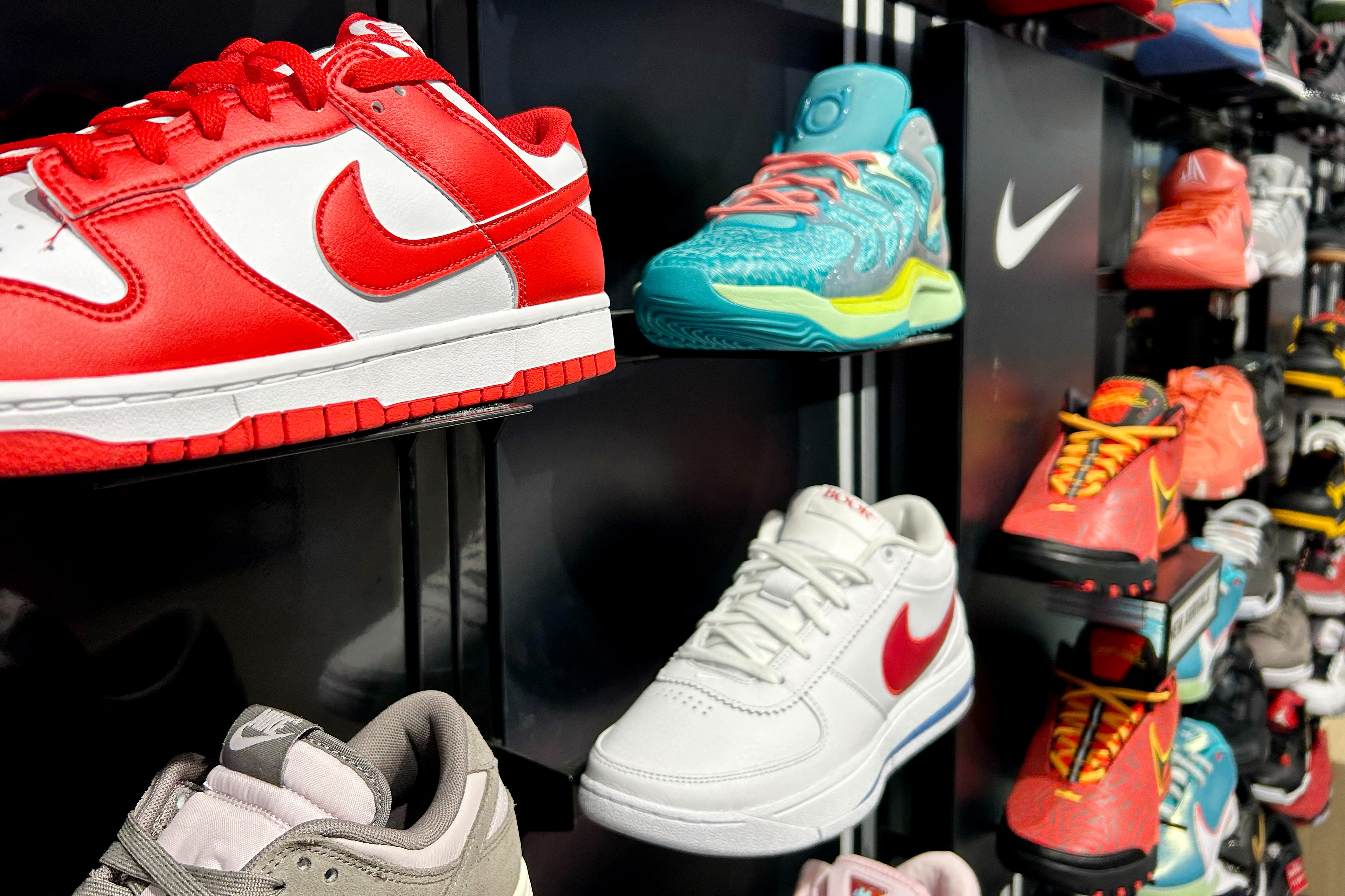 Various Nike sneakers on display, including red, white, and blue styles, arranged on shelves in a store setting