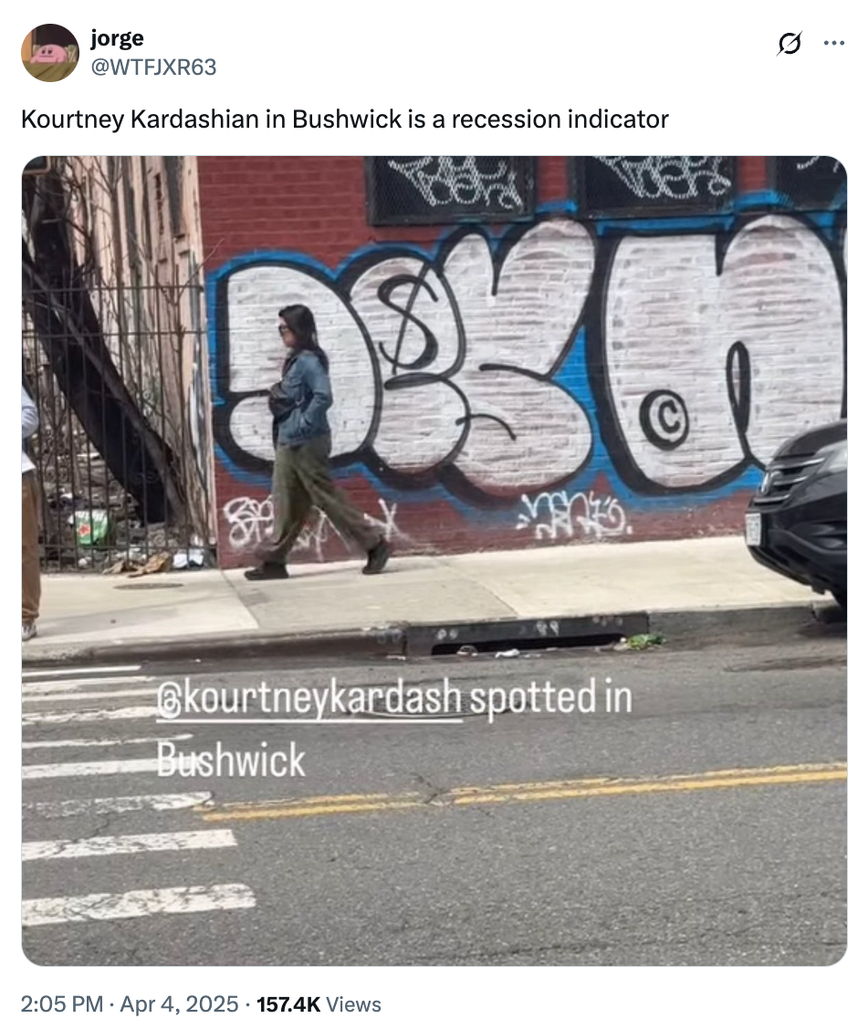 Person walking on a sidewalk in front of graffiti-covered wall. Overlay text mentions Kourtney Kardashian spotted in Bushwick